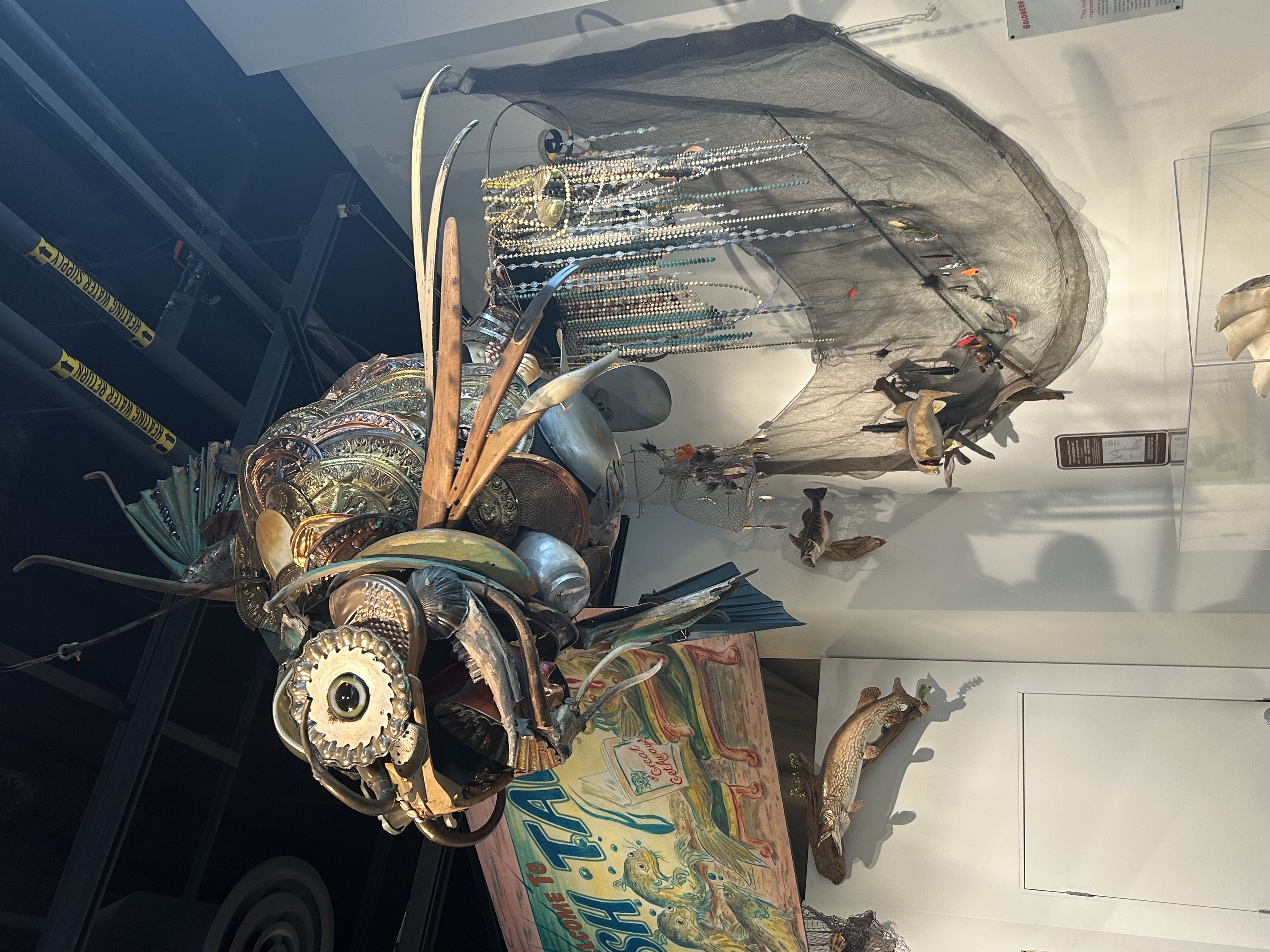 large decorative fish sculpture made out of glass, metal, and beads, hanging from ceiling